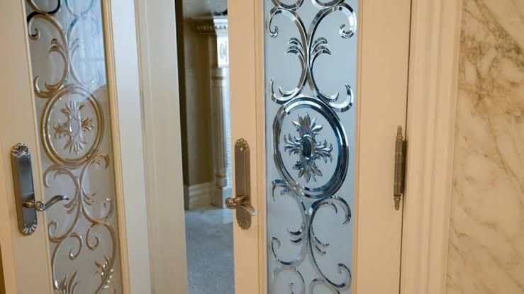 Close view of door panels with carved and beveled floral and scroll designs in the glass