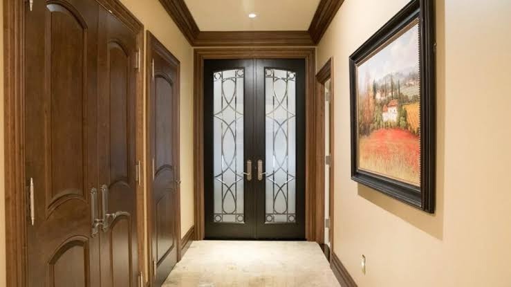 Hallway with dark wood double doors filled with beveled decorative glass