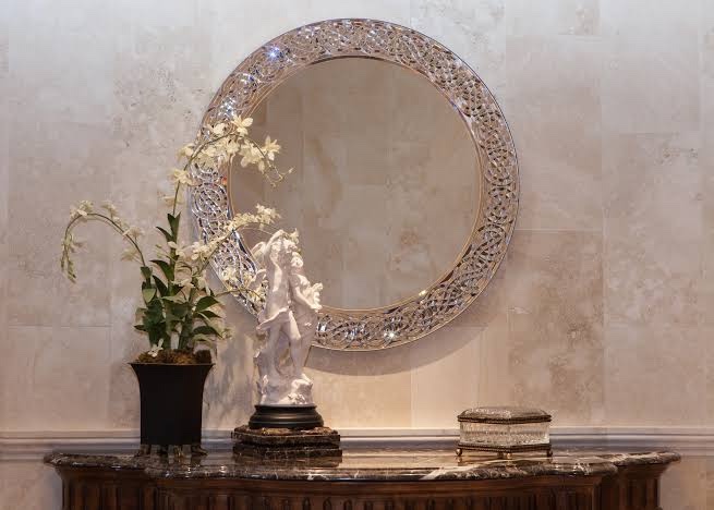 Round mirror with an ornate openwork frame above a marble console